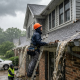 Clogged gutter system causing water overflow and roof damage during heavy rain at a residential property.