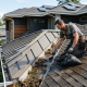 Professional roofer cleaning blocked roof valleys to improve roof drainage and help prevent costly roof damage.